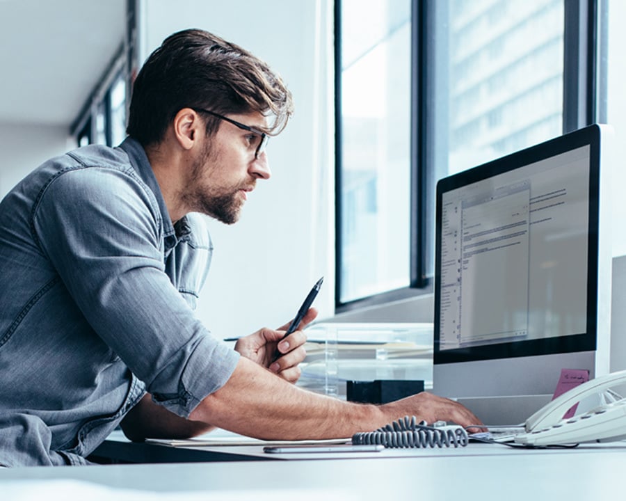 A man seated at a desk, focused on his computer.