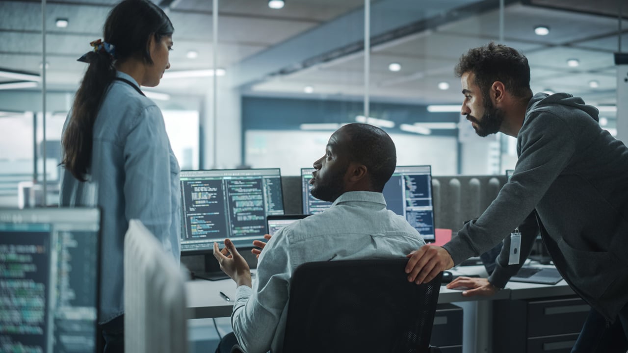 Three professionals engaged in computer work.