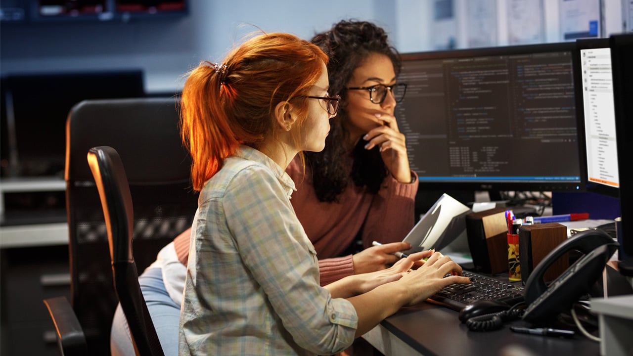 Two women engaged in work at computer screens.