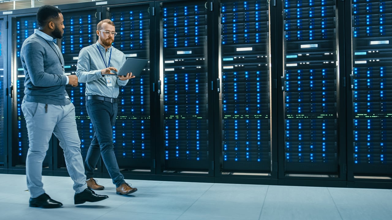 Two men in a data center, standing before a wall of servers.