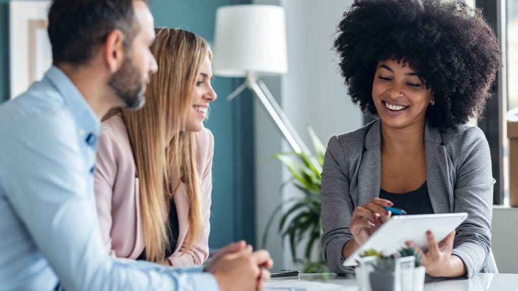 Business meeting with three individuals using a tablet for collaboration.