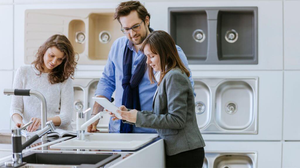 Three people examining a kitchen sink
