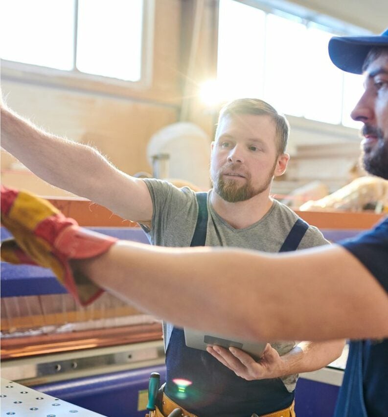 Two men collaborating on tasks in a factory