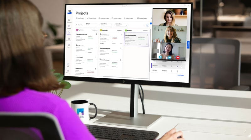 A woman at a desk participating in a video conference on her computer screen