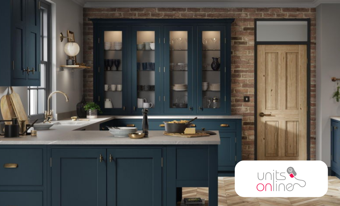 Traditional kitchen with navy blue cabinetry, glass-fronted display units, exposed brick wall, and a natural wood door. Units Online logo is displayed in the bottom-right corner.