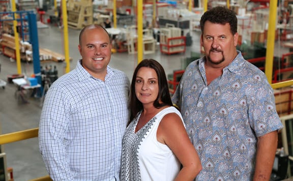 Three Avanti employees standing on a yellow-railed balcony inside a factory