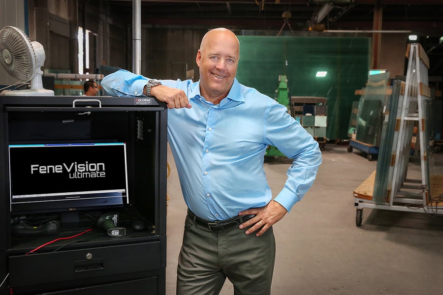 A GlasPro representative standing confidently in the production facility next to a workstation showcasing FeneVision software.