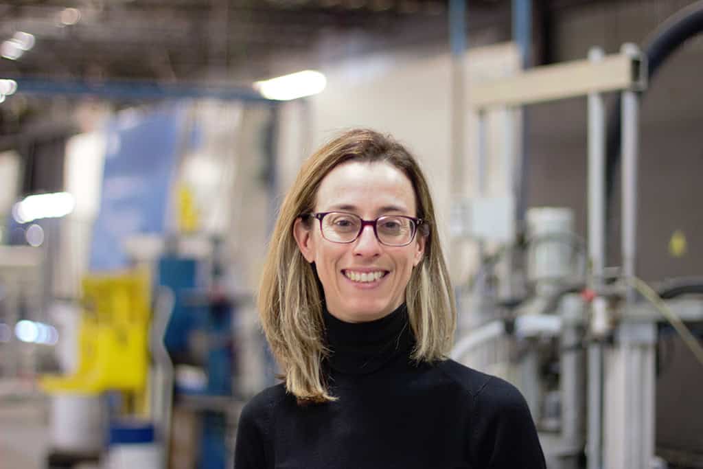 A woman stands in a factory setting