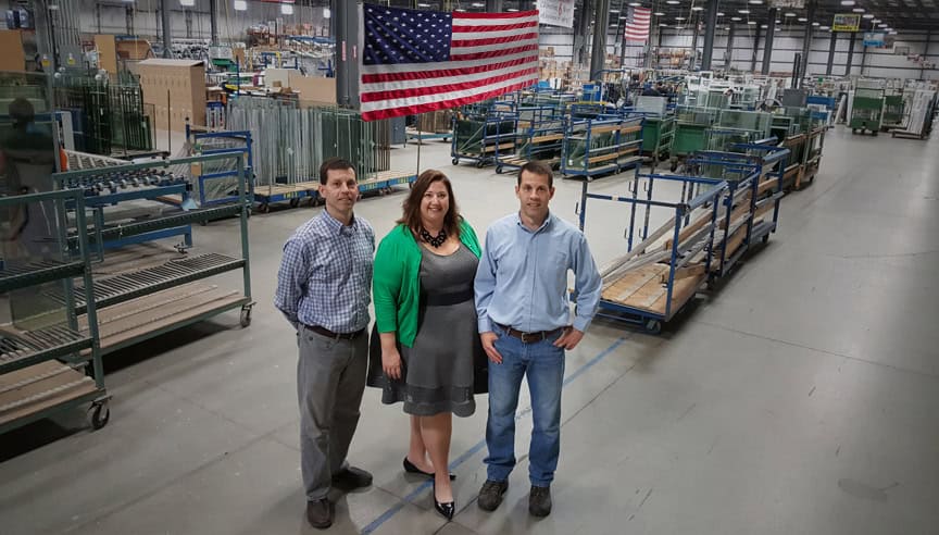 Three individuals stand before a large warehouse