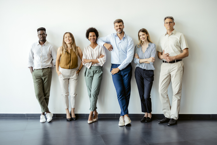 Group portrait of business people posing against office wall background