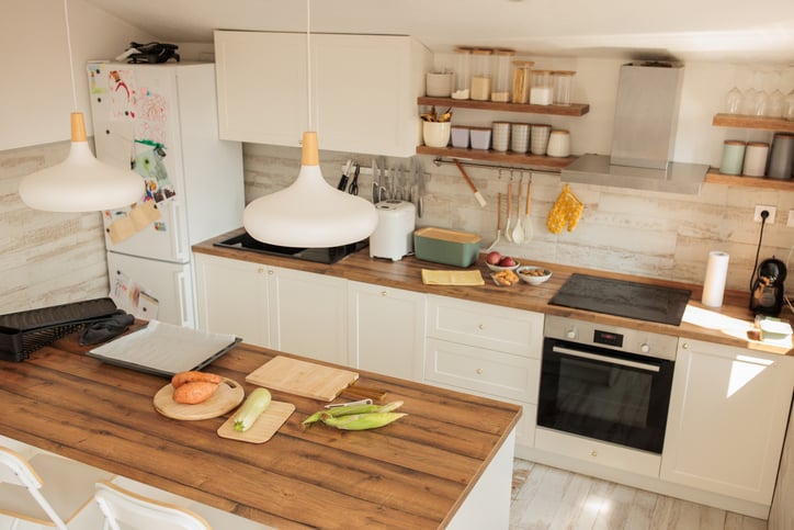 White kitchen interior with wooden kitchen island and a brown wooden countertop with a sink - stock photo