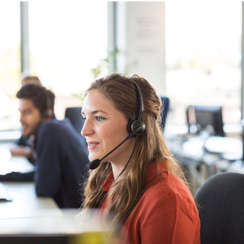 Smiling female customer representative wearing headphones working in office